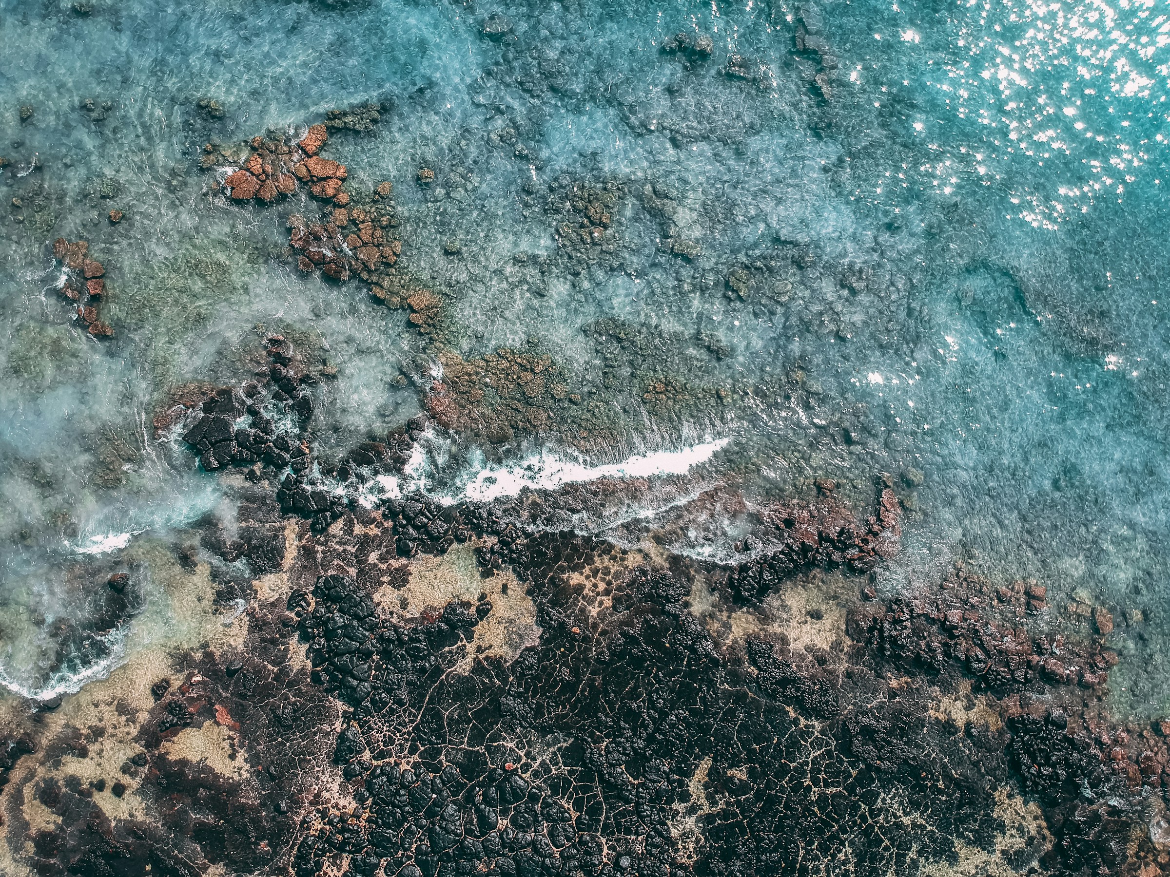 Sunlight sparkling on turquoise sea and coastal rocks at Blue Bay near Mahébourg, Mauritius